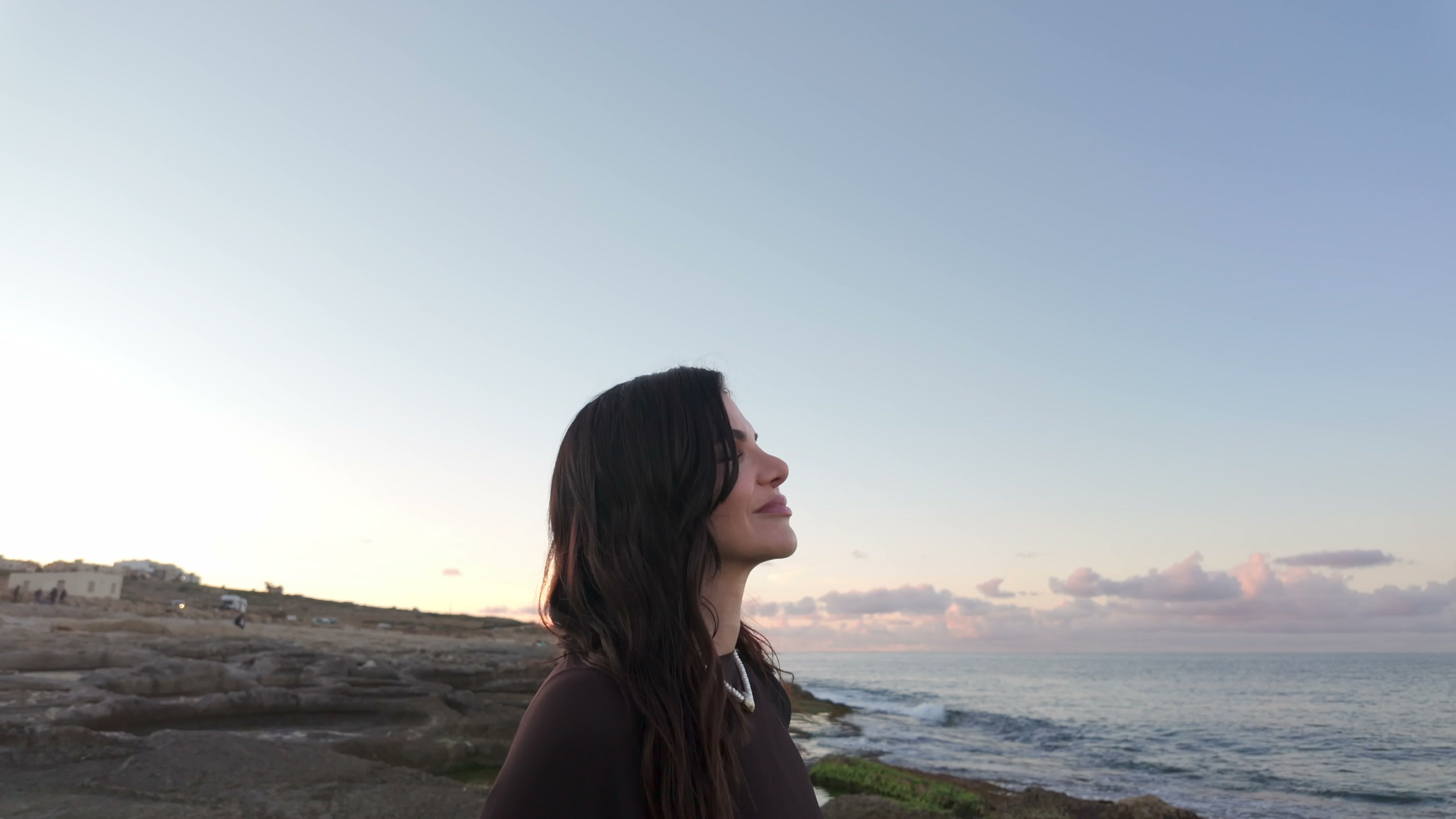 Agata Sadowska at the shore, face lifted to the sky at dusk